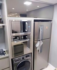 a metallic refrigerator freezer sitting inside of a kitchen next to a washer and dryer