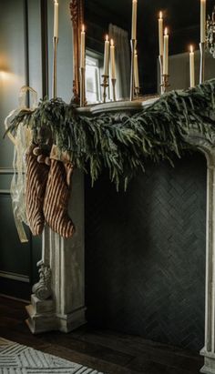 stockings hanging from the mantle in front of a mirror with candles and wreaths on it