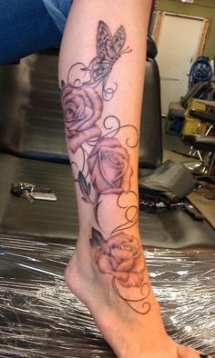 a woman's leg with roses and a butterfly tattoo on her left calf area