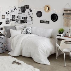 a bedroom with white bedding and black and white decorations on the wall above it