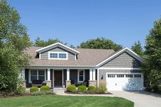 a house that is in the middle of some grass and trees with bushes around it