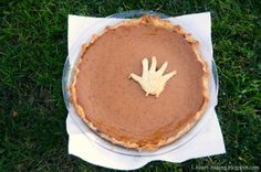 a pie with a hand on it sitting on top of a napkin in the grass