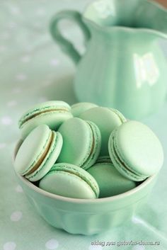 green macaroons in a bowl next to a teapot and polka dot tablecloth