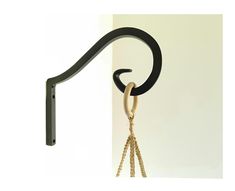 a black and gold hook on a white wall with a chain hanging from it's end