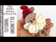 a small crocheted animal with a red hat on it's head is in someones hand