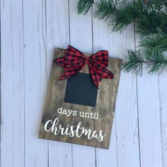 a wooden sign that says days until christmas with a bow hanging from the front on a white wood background