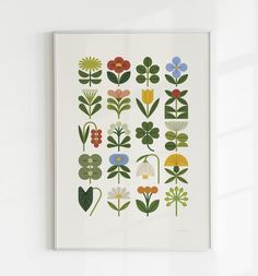 an art print with flowers and leaves on the wall in front of a white window