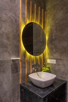 a bathroom with a round mirror above the sink and wooden accents on the wall behind it