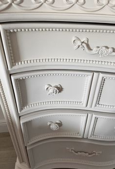 an ornate white dresser with drawers and knobs