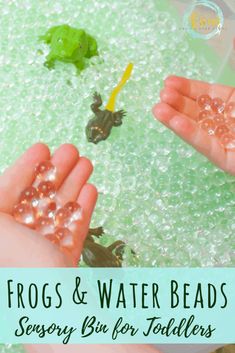 two hands are holding small beads in the water with froggies and other toys behind them