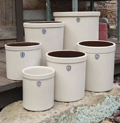 four white buckets sitting next to each other with the words fermenting food in a stoneware crock