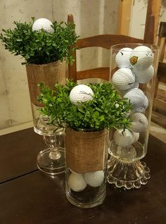 three vases with plants and golf balls in them on top of a wooden table