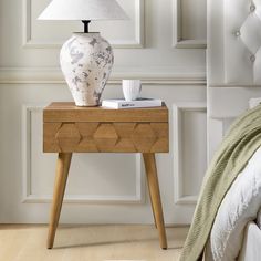 a table with a lamp on it next to a bed