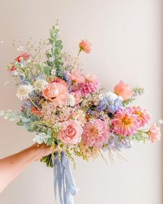 a person holding a bouquet of flowers in their hand with the other hand on it