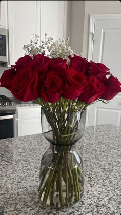 a vase filled with red roses on top of a counter