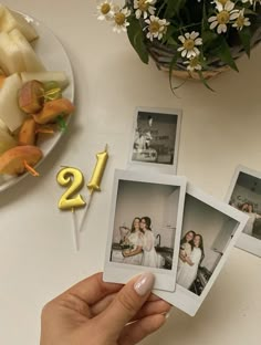 a person holding up four photos with the number twenty two on them and flowers in the background