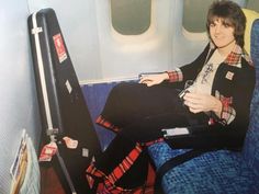 a man sitting on an airplane seat holding a drink