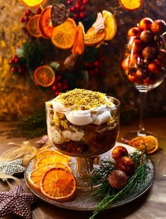 a dessert with oranges and other fruit on a plate next to a glass of wine