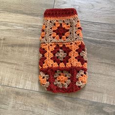 an orange and brown crocheted bag sitting on top of a wooden floor