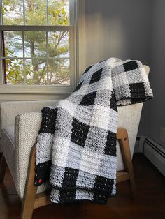 a black and white blanket sitting on top of a wooden chair next to a window