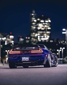 the back end of a blue sports car parked in front of a cityscape