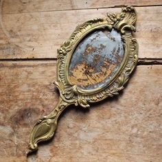 an old mirror sitting on top of a wooden table next to a wall with peeling paint