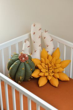 two stuffed animals sitting on top of a crib next to a pumpkin and cactus