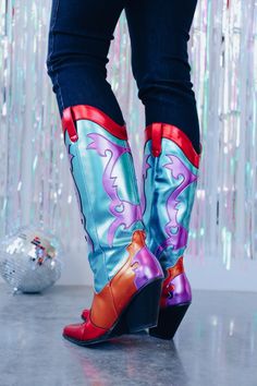 These colorful boots are a show stopper and will have you standing out in the crowd! They are meant for a fabulous party so if you are going to the big easy these cuties are a must! These bold boots consist of a teal shaft with a purple flame design on the front and back shaft plus the heel, a red trimmed top with pull tabs and red pointed toe, and an orange vamp that extends around the heel. Shaft height: 15" 15" calf opening Heel height: 3" Fits true to size ﻿ *Screen resolution/lighting may a