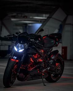 a black motorcycle with red lights on it's headlight is parked in a parking lot