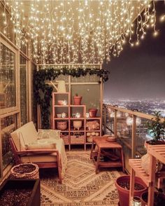 a balcony with lights strung from the ceiling and potted plants in pots on the floor