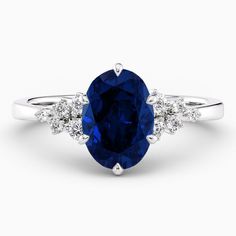 an oval blue sapphire and diamond ring with three stone side stones on the band, set in 18k white gold