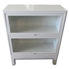 a white glass cabinet with two shelves on one side and an open drawer on the other