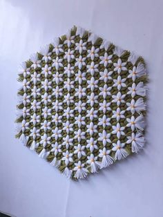 a green and white wall hanging with flowers on it