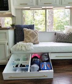 a white couch sitting under a window in a living room next to a wooden floor