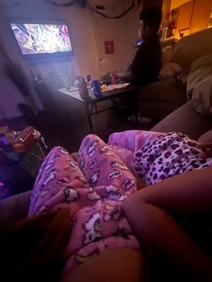 a person laying on a couch in front of a flat screen tv with the lights on