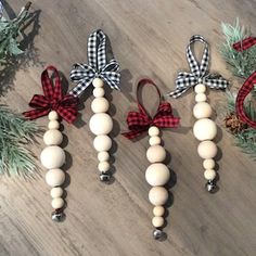 three wooden beads with bows on them are sitting next to pine cones and evergreen branches