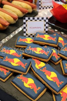 cookies decorated with red and yellow designs are on a table next to hot dogs in buns