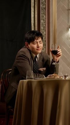 a man sitting at a table with a glass of wine