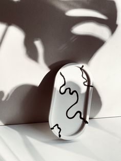 a white and black object sitting on top of a table next to a shadow cast wall