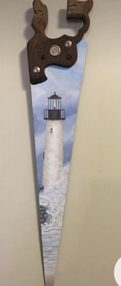 a knife shaped like a lighthouse hanging from the side of a wall with a light house painted on it