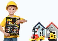 a young boy holding a sign next to toy construction trucks and building blocks on white background