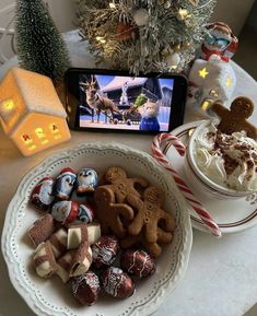 a plate with cookies, marshmallows and candy on it next to a cell phone