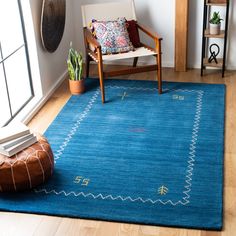 a living room area with a blue rug and wooden chair in front of a window