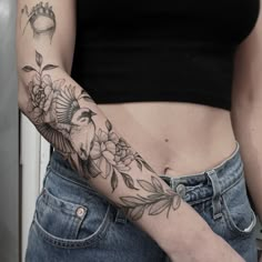 a woman's arm with a bird and flowers tattoo on the left side of her body