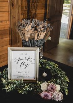 a sign that says let the sparks fly on top of a table with flowers