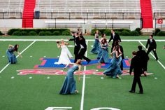 a group of people standing on top of a field next to an american football field