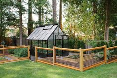 a small greenhouse in the middle of some grass