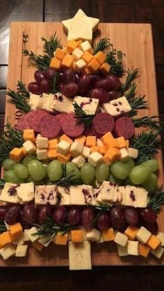 a christmas tree made out of cheese, grapes and meats on a cutting board