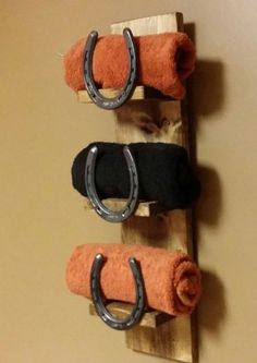 three pairs of black, orange and white towels hanging on a wooden rack with horseshoes