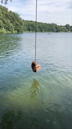 a person hanging from a rope in the water